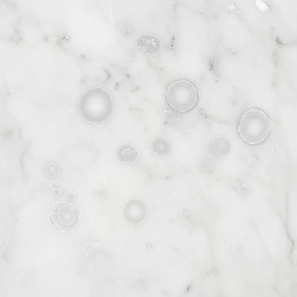 Close-up of marble surface showing etch marks from acidic substances, highlighting the need for anti-etch sealing