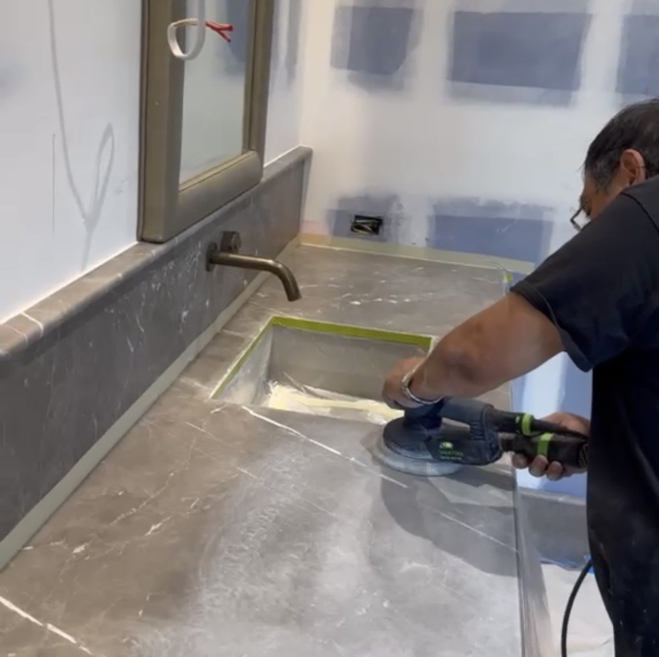 Technician polishing a marble vanity with an orbital tool during surface restoration.