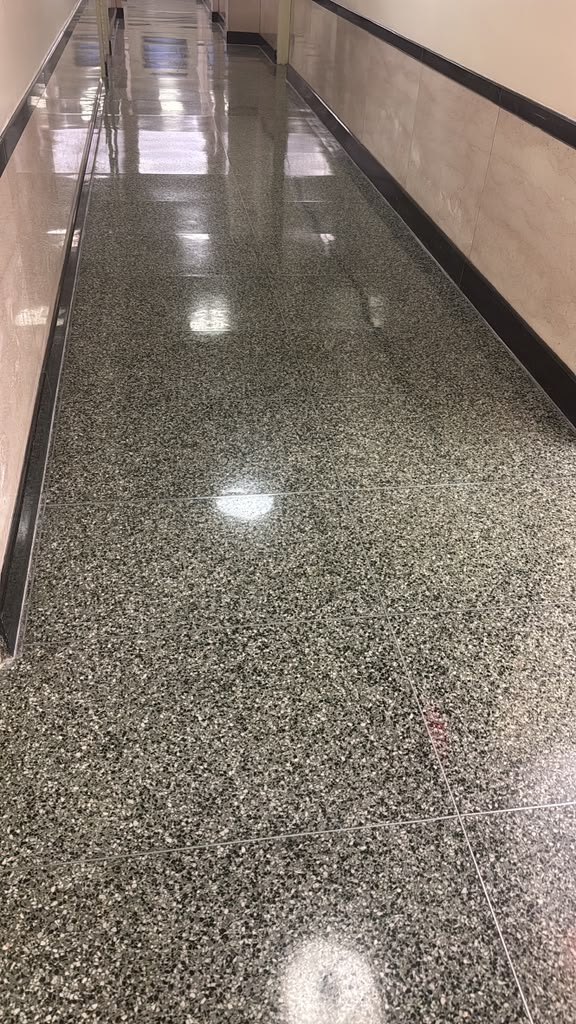Polished terrazzo floor in a long commercial corridor with light-colored walls.